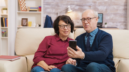 Obraz premium Old man and woman having a video call using their smartphone