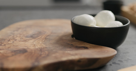 Fototapeta na wymiar small mozzarella balls in black bowl with empty on olive wood board