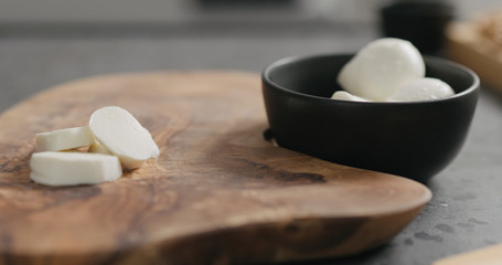 sliced small mozzarella balls on olive wood board