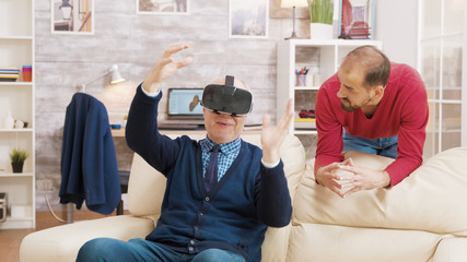 Fototapeta premium Nephew teaching his grandfather how to use virtual reality headset