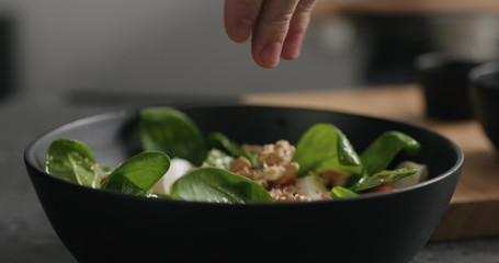 Closeup decorating salad from spinach, tomatoes and mozzarella with walnuts