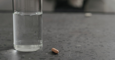 Glass of water and orange pill on terrazzo countertop