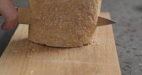 man slicing ciabatta with bread knife on oak board