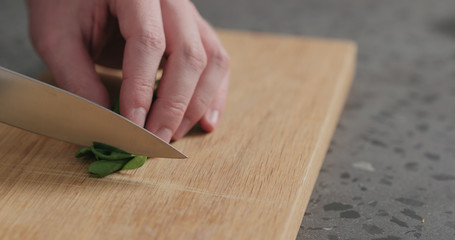 man chopping fresh spinach leaves on oak cutting board