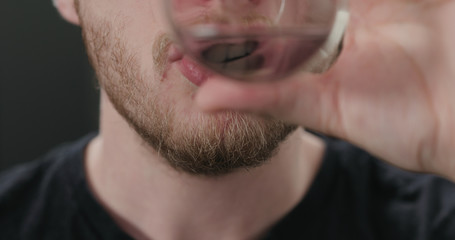 closeup shot of bearded man drinking water from glass