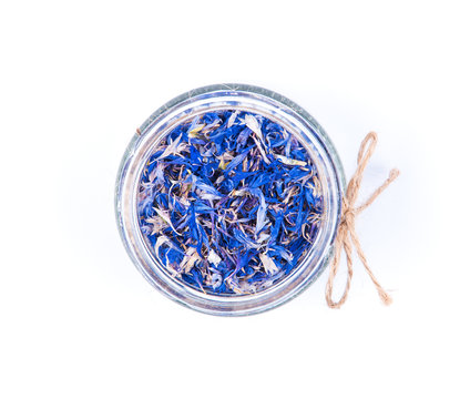 Blue cornflower centaurea dried petals in a glass jar isolated on white background.