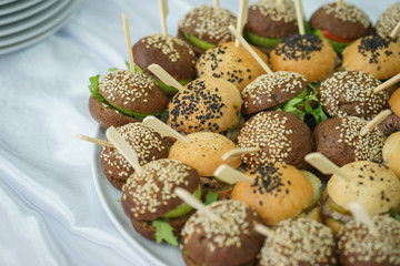 Mini burgers with meat and fish on the table prepared for the guests of the event.