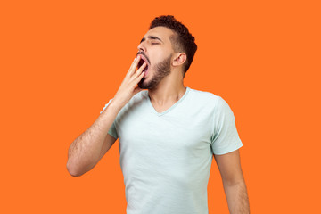 I need rest. Portrait of sleepy brunette man with beard in casual white t-shirt yawning and...