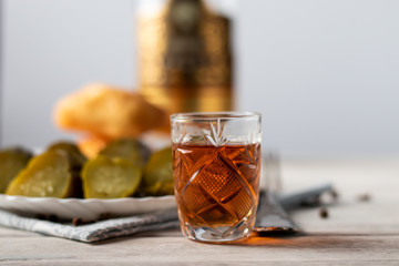 on a wooden table is a glass of cognac, a snack of a piece of dark chocolate and a bottle of alcohol