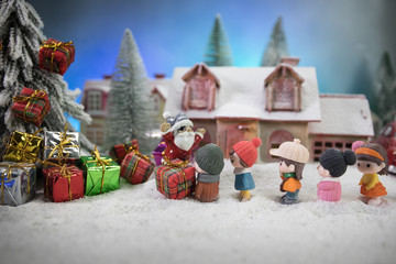 Christmas and New Year holidays concept. Little decorative cute small houses in snow at night in winter, Fir tree standing on snow with beautiful holiday decorated background