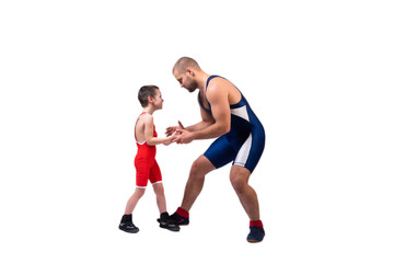 Fototapeta na wymiar A wrestler boy in a sports tights wrestles with an adult male wrestler on a white isolated background. The concept of child power and martial arts training. Teaching children Greco-Roman wrestling