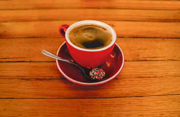 a cup of coffee and small cookie is on the table