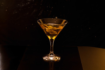 martini with olives on black background
