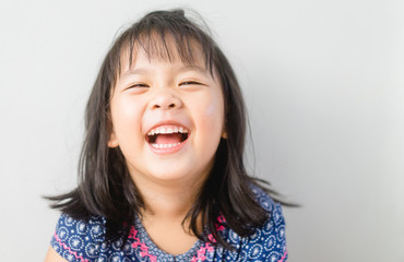 Happy Little asian girl child showing front teeth with big smile and laughing: Healthy happy funny...