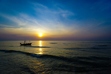 Fototapeta na wymiar Colorful Sunrise with Sand and boat on the ocean at Huahin Thailand .