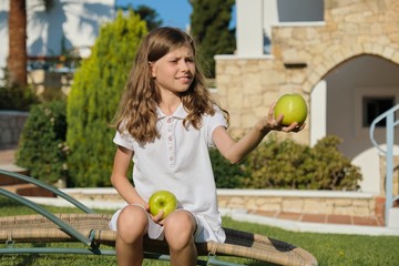 Girl child tossing, playing, juggling green apples, sunny summer day