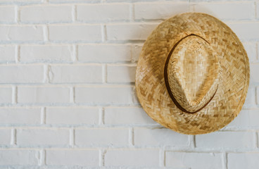 Straw hat hanging on a white brick wall