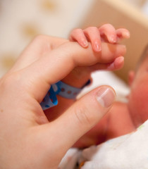 The baby clings to his mother's finger