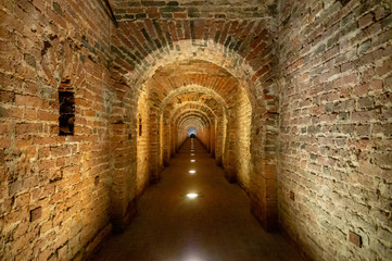 Fototapeta na wymiar Brick archway made of red bricks as a passage between the two wings of a medieval castle. Granite stone an brick built Interior passage to bastions