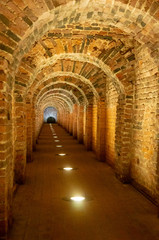 Fototapeta na wymiar Brick archway made of red bricks as a passage between the two wings of a medieval castle. Granite stone an brick built Interior passage to bastions