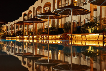 Illuminated hotel with a swimming pool at night. Evening lights at resort