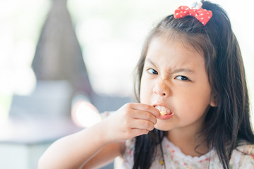 Hungry face and enjoy eating concept.Little asian girl enjoy eating with french fries with cheese on a plate in lunch time at restaurant.