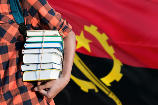Angola national education concept. Close up of teenage student holding books under his arm with country flag background.