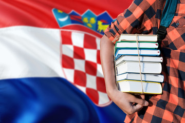 Croatia national education concept. Close up of teenage student holding books under his arm with country flag background.