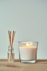 Burning candle with aroma sticks in a glass bottle