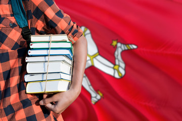 Isle Of Man national education concept. Close up of teenage student holding books under his arm with country flag background.