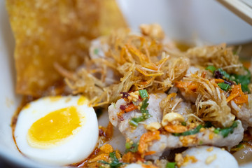 Spicy tom yum noodle with pork and meat ball and egg.