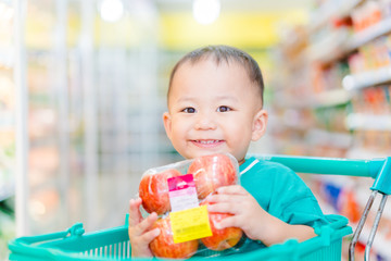 Funny little asian boy child smile and laughing in hypermarket, little asian toddler boy sitting in the trolley cart during family shopping in supermarket.