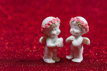 Lovely of little cupid or small angel standing together on red bokeh background, good feeling for lover, romantic symbol for your design, gift card. Holiday valentine and love concept.