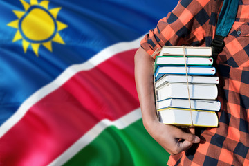 Namibia national education concept. Close up of teenage student holding books under his arm with...
