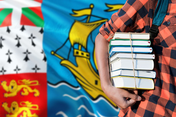 Saint Pierre And Miquelon national education concept. Close up of teenage student holding books under his arm with country flag background.