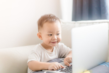 Portrait of a little toddler boy watching laptop and exciting face.Little asian boy child with...