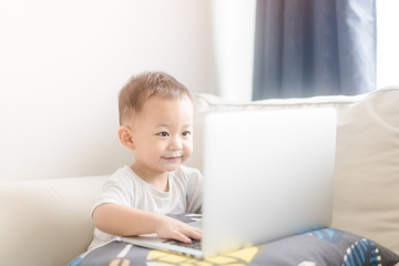 Portrait of a little toddler boy watching laptop and exciting face.Little asian boy child with...