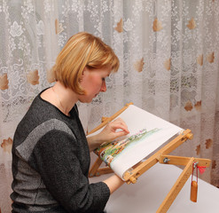 Young smiling woman embroiders on a frame