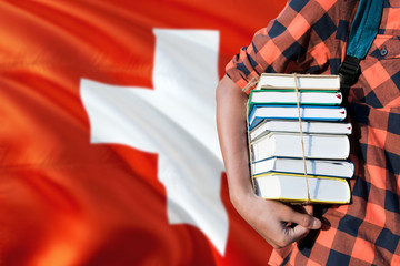 Switzerland national education concept. Close up of teenage student holding books under his arm with country flag background.
