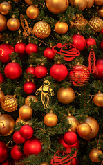 Christmas tree with gold bauble ornaments. Decorated Christmas tree closeup. Balls and illuminated garland with flashlights. New Year baubles macro photo with bokeh. Winter holiday light decoration