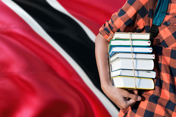 Trinidad And Tobago national education concept. Close up of teenage student holding books under his arm with country flag background.