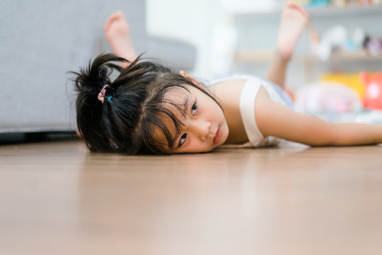 Little girl lying and lazy moment on laminate floor.Child girl tired and low battery want to sleep at home.