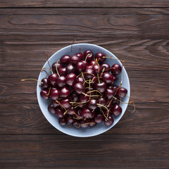 Ripe sweet cherries in a blue bowl, top view