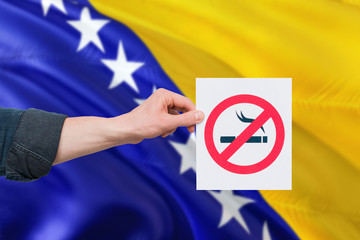 Bosnia Herzegovina health concept. Hand holding paper with no smoking sign over national waving...