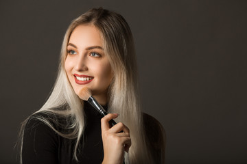 Obraz premium beautiful young woman with her hair with makeup with makeup in hands on a gray background