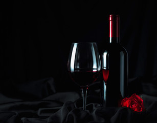 Red wine and red rose on black background.