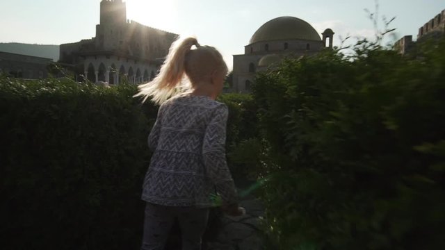 caucasian blond young girl running away in maze of bush in castle slow motion