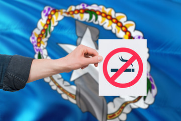 Northern Mariana Islands health concept. Hand holding paper with no smoking sign over national waving flag. Quit smoke theme.