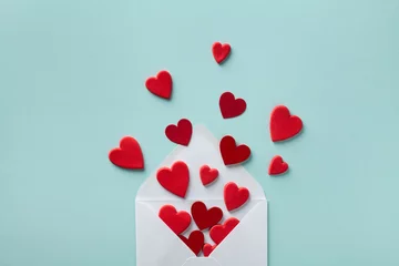 Valentinstag-Grußkonzept. Umschlag und rote Herzen auf Draufsicht des blauen Hintergrundes. Flach liegen. © juliasudnitskaya