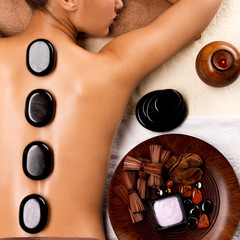 Young woman getting hot stone massage in spa salon.